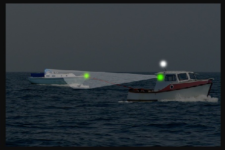 A dismasted yacht being towed by a small motor boat - tow line is illuminated