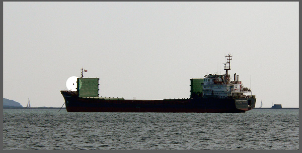 A merchant vessel - showing a ball forward to indicate she is at anchor