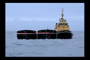 A vessel towing two barges alongside