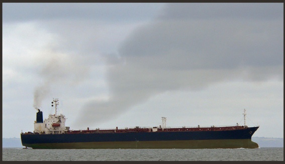 A large merchant vessel emitting smoke